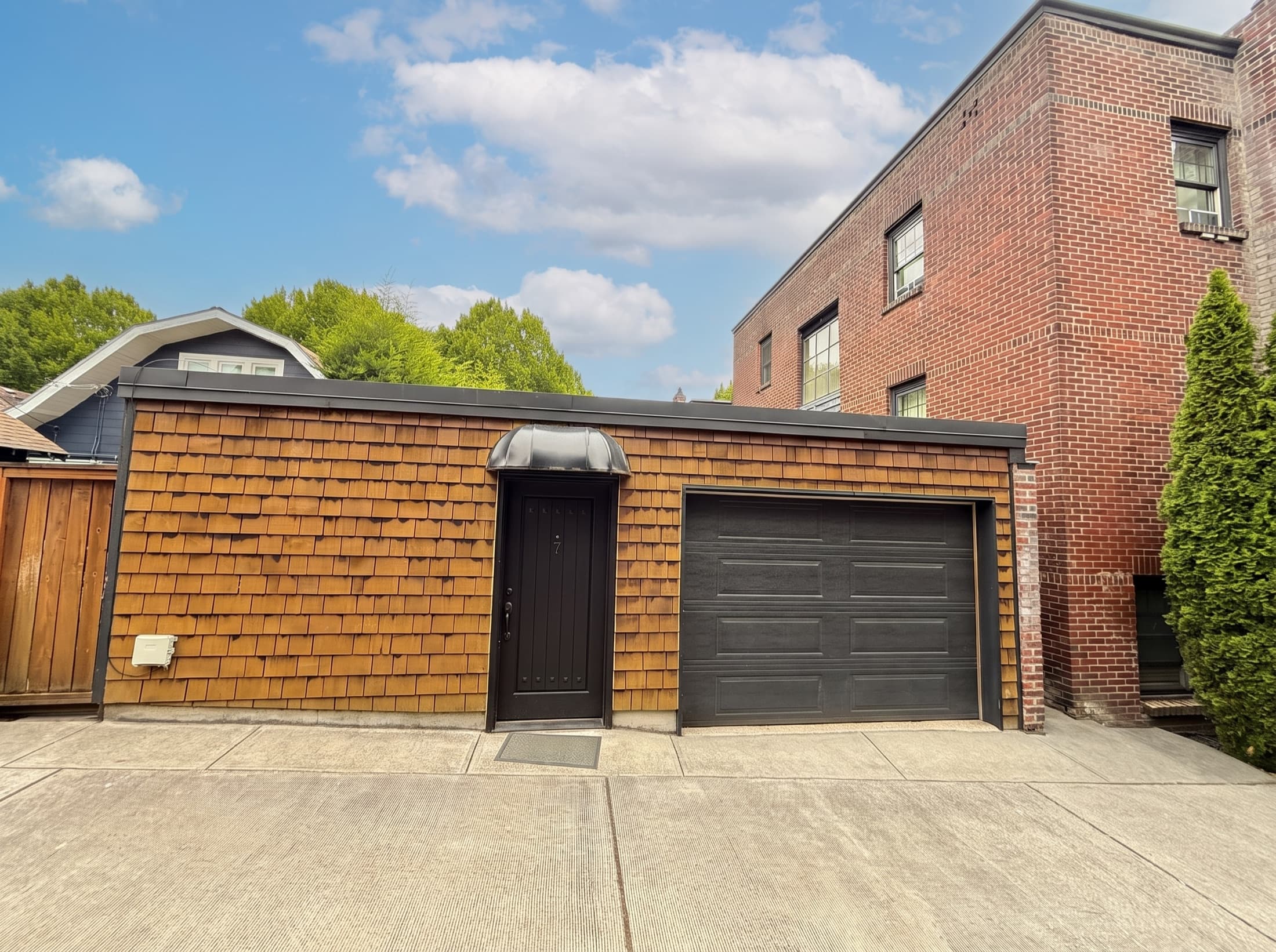 Front of the cedar-shingle studio with its black entry and roll-up door